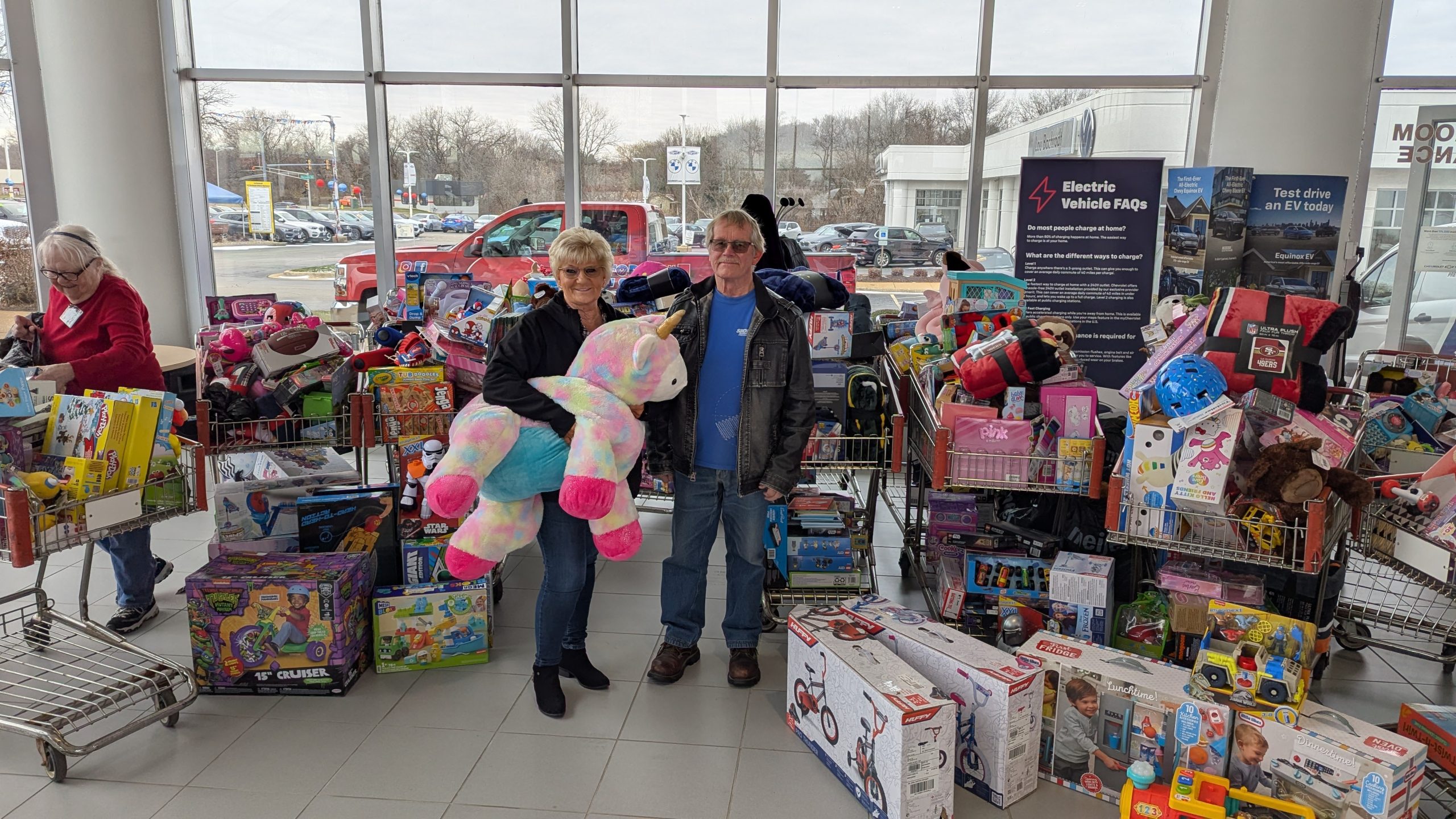Two Bachrodt On State standing in front of all the toy drive donations.