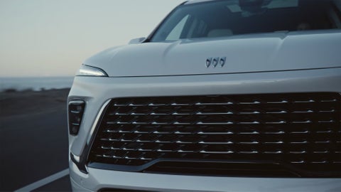 A person is shown interacting with a smartphone to connect to a Lincoln vehicle across the street. | Lou Bachrodt Family of Dealerships in Rockford IL